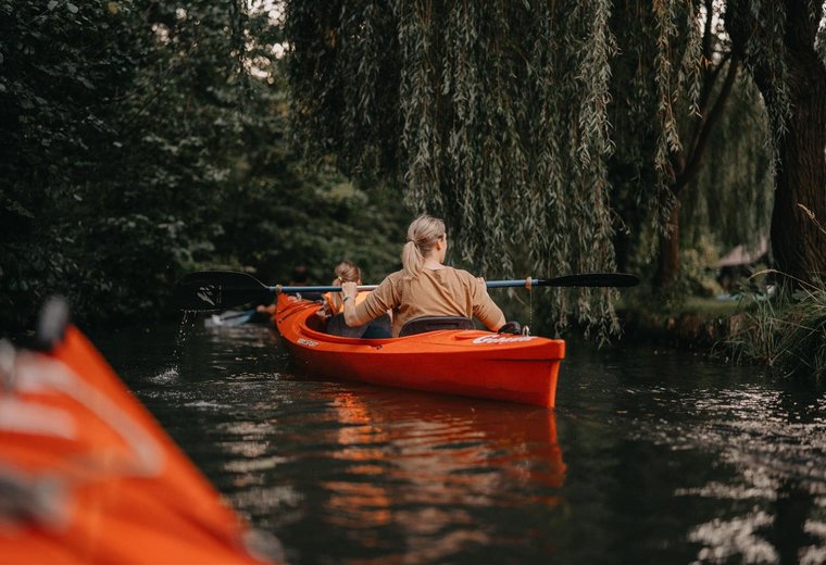 Frau paddelt im roten Boot im Fluss