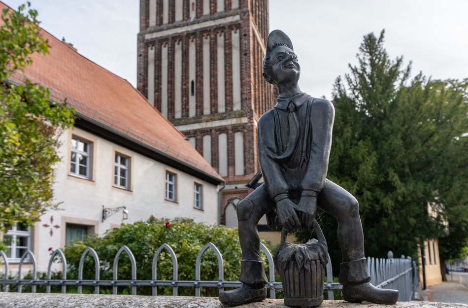 Calau Figur in Innenstadt im Hintergrund eine Kirche