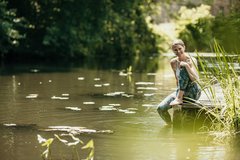 Frau sitzt nach Yoga in Sportkleidung am Fließ im Spreewald und entspannt