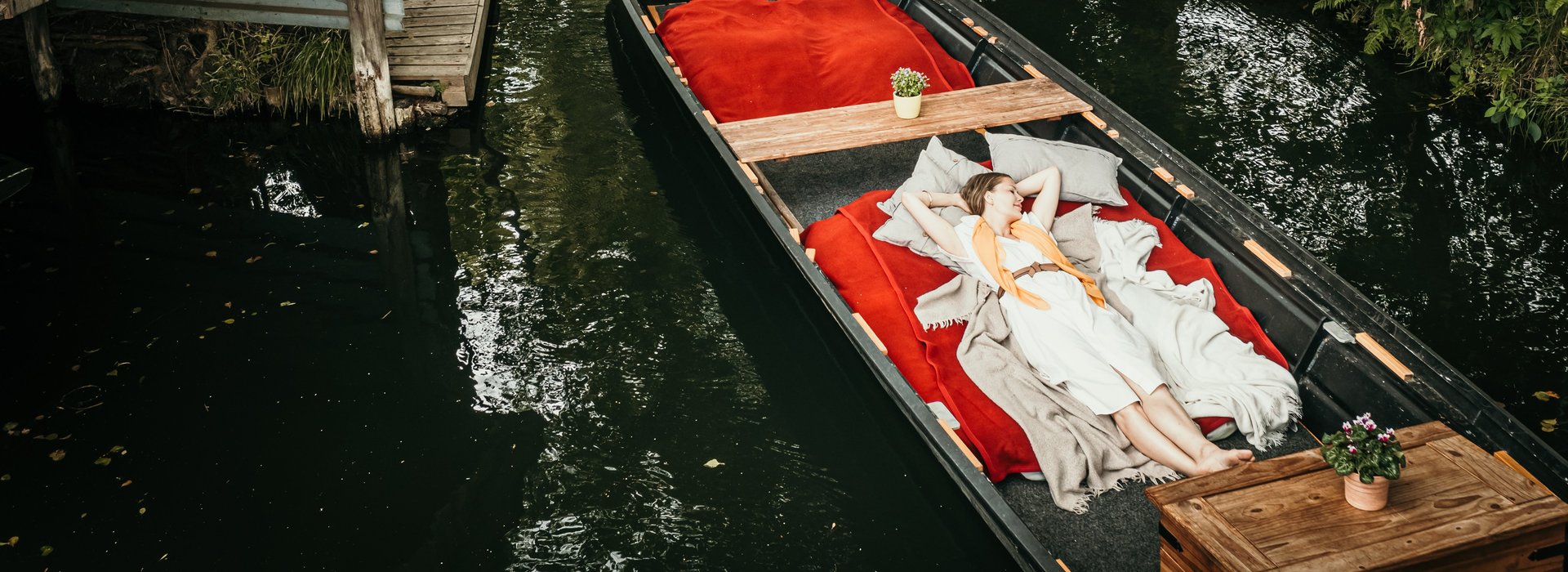 Frau liegend auf Kahn wird durch Fließe im Spreewald gefahren