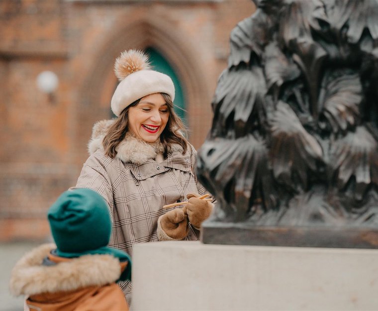 Frau steht mit Kindern vor Statue in Cottbus