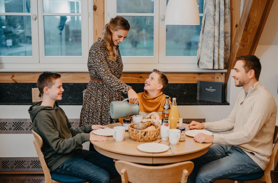 Familie sitzt an Küchentisch zum Frühstück