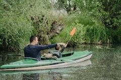 Mann mit Kind paddelt im grünen Boot im Spreewald