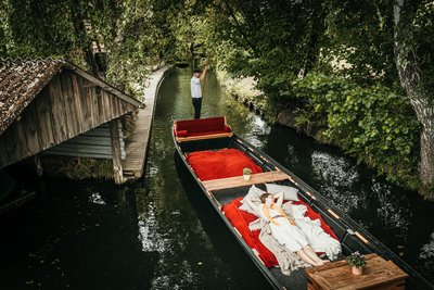Frau liegend auf Kahn wird durch Fließe im Spreewald gefahren
