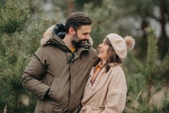 Frau und Mann lächeln sich umarmt an bei Winter Spaziergang