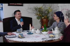 Moderator sitzt am Kaffeetisch in Museum und unterhält sich mit 2 älteren Damen
