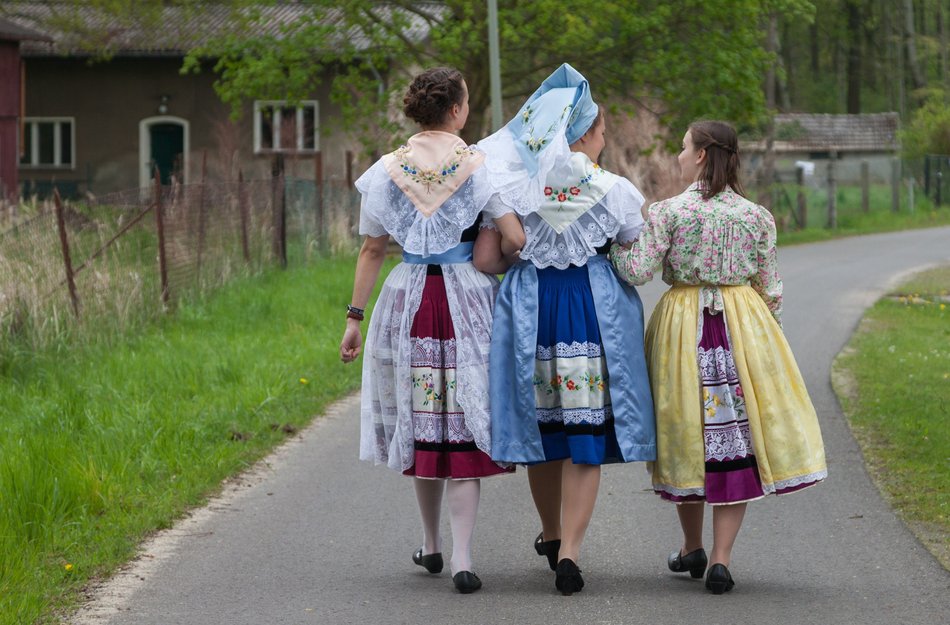 Drei Frauen in traditionellen Trachten aus dem Spreewald man sieht die Rücken sie laufen auf einem Weg und unterhalten sich