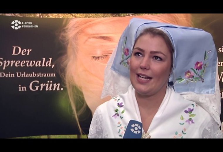 Frau in klassischer Spreewaldtracht führt Interview auf Messe