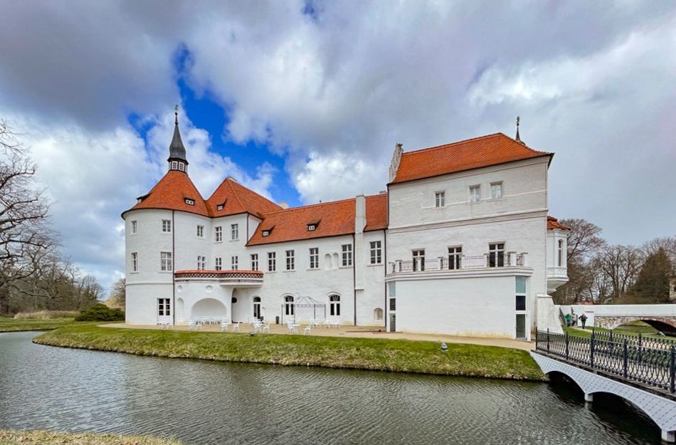 Schloss am See mit Brücke als Zugang im Bild rechts