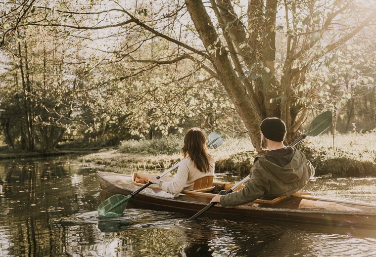 Frau und Mann im Boot paddeln durch Spreewald Fließ in Herbststimmung
