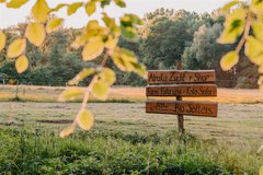 Holzschild mit Entfernungsangaben auf Feld