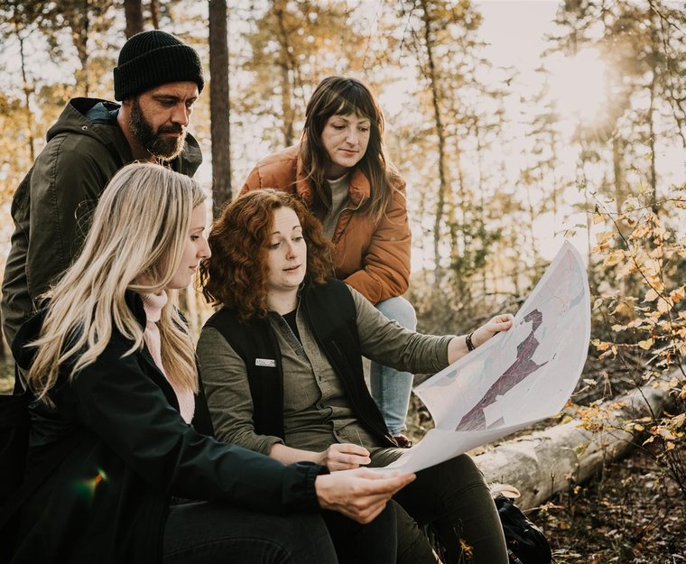 Gruppe im Wald schaut auf Karte