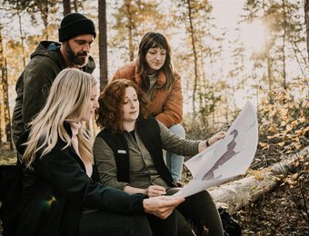 Gruppe im Wald schaut auf Karte