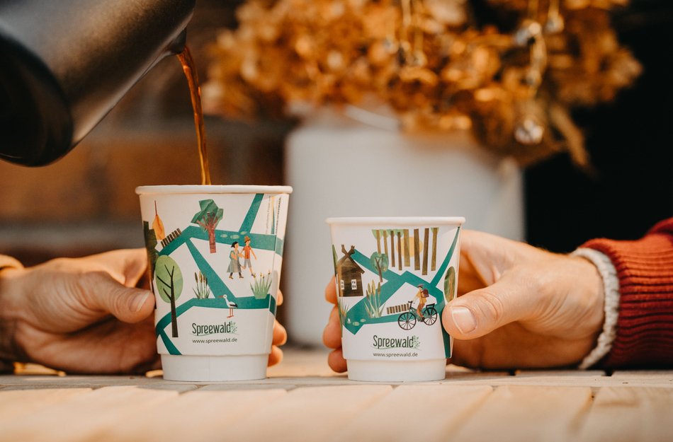 Becher mit Spreewald Motiven und Hände in Nahansicht die sie halten