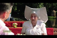 Alte Dame in klassischer Tracht erzählt mit Moderator