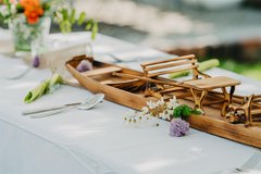 dekorierter Mittagessen Tisch mit kleinem Holzkahn als Deko und Blumen